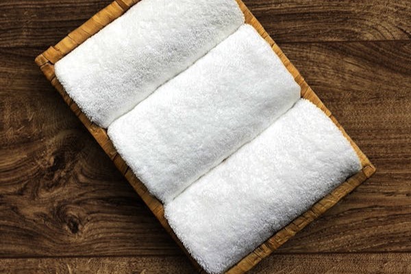 Rolled white spa towels with candle
